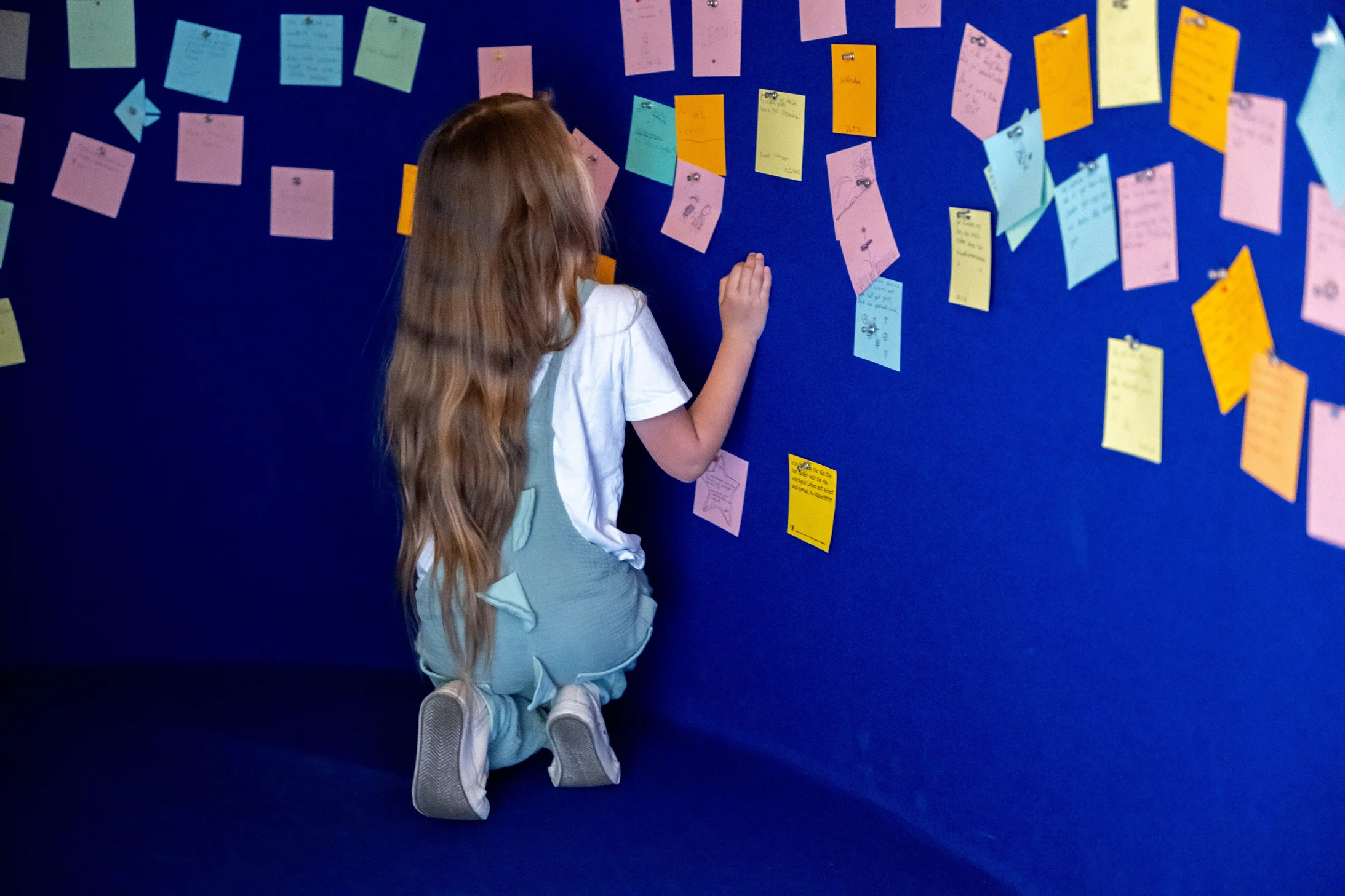 Kind beteiligt sich mit Notizzetteln an einer Ideensammlung im Besucherzentrum in Trogen. Symbol für Kinderrechte, Partizipation, Mitbestimmung und Meinungsäusserung im Schulalltag.