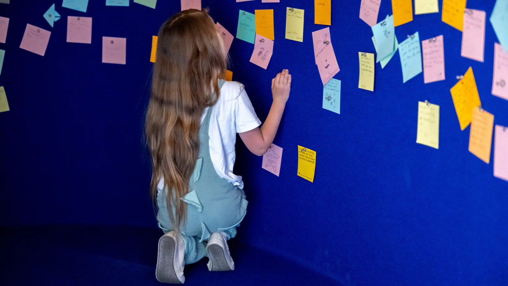 Kind beteiligt sich mit Notizzetteln an einer Ideensammlung im Besucherzentrum in Trogen. Symbol für Kinderrechte, Partizipation, Mitbestimmung und Meinungsäusserung im Schulalltag.
